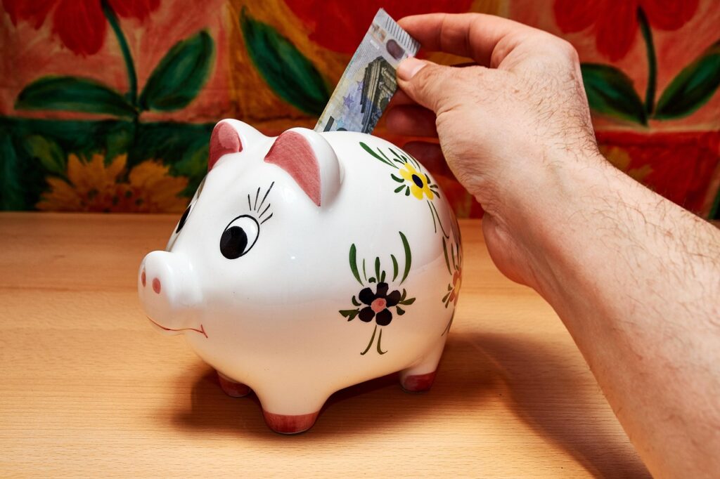 A person putting dollar cash in a white piggy bank 