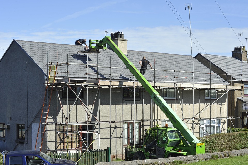 A home is being repaired and two men on the roof of house