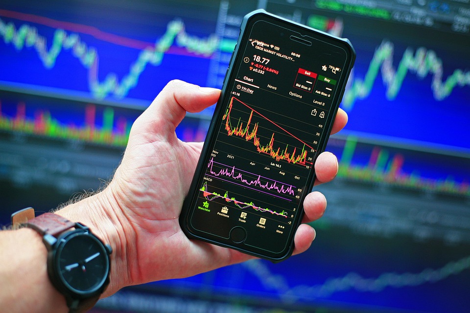 A person holding a phone and trading graph is showing in phone 