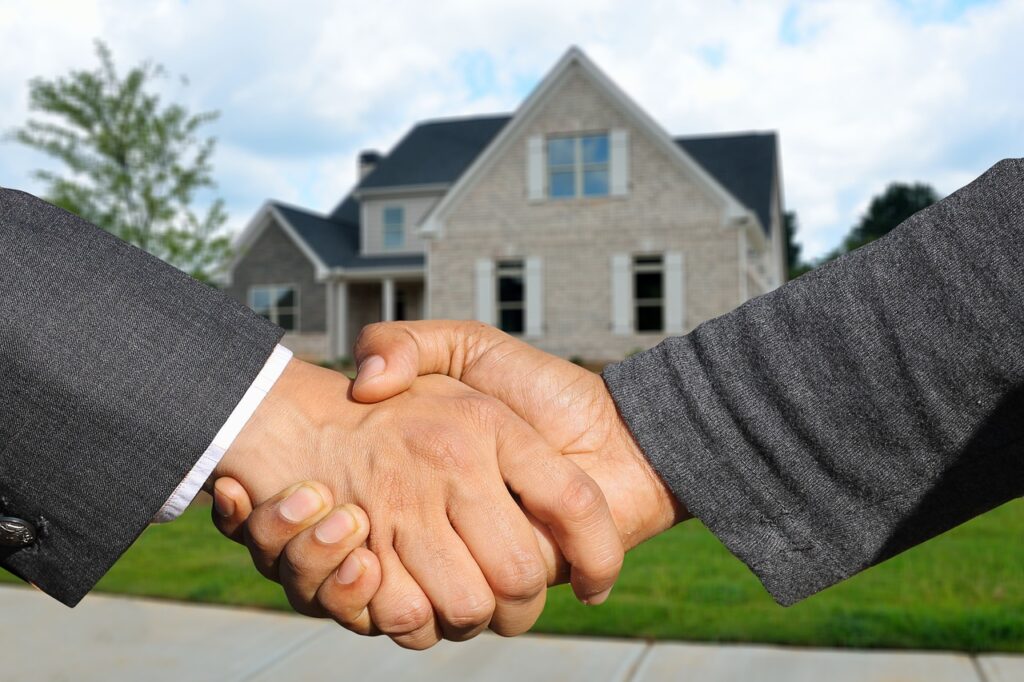 Investing in real estate Two men shaking hand and a beautiful home is showing on background
