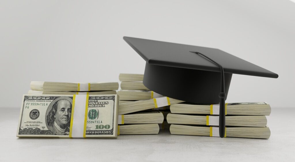 Stacks of hundred-dollar bills lie on a table with a graduation cap resting on top, symbolizing financial investment in education.